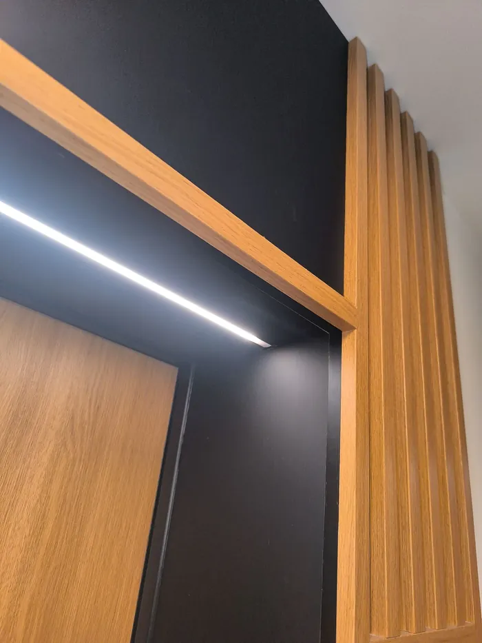 Listwa LED nad drzwiami w portalu z lamelami, Apartamenty Pustułeczki w Warszawie