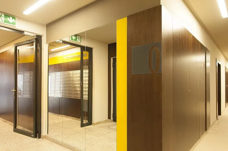Korytarz w Apartamentach Konstruktorska 10 z okładziną w ciemnym fornirze i numerem piętra