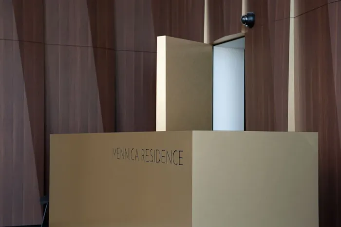 Lada recepcyjna z napisem Mennica Residence przed ścianą z ciemnych paneli