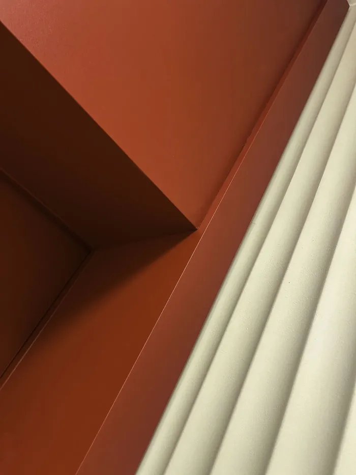 Detal narożnika: czerwona płaszczyzna i jasne pionowe panele