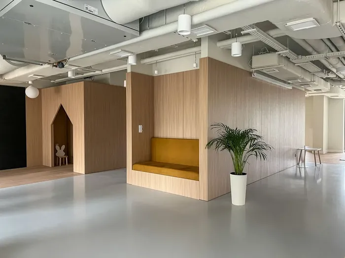 Drewniane zabudowy z wnękami do siedzenia w pomieszczeniu wspólnym budynku Modern Mokotów