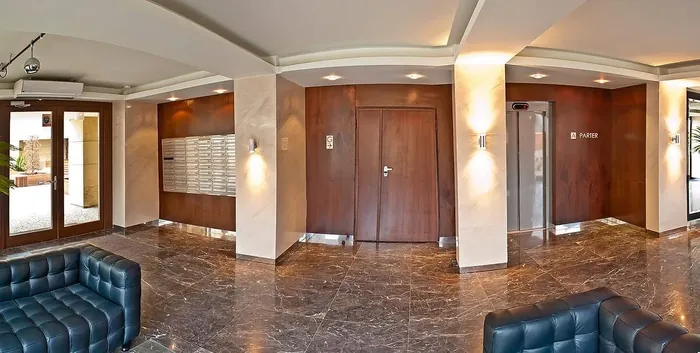 Hol Wilanów Residence z ciemnymi panelami wokół drzwi, windy i skrzynek pocztowych